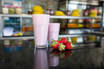 Obraz na płótnie Canvas Strawberry smoothie or milk shake on the table with strawberries