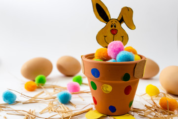 Easter eggs of different colors lying on the table next to the green  and the rabbit.