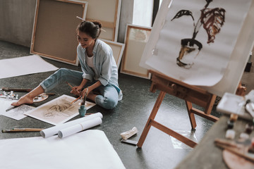 Full length of happy woman sitting on the floor of art studio
