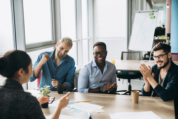 Colleagues rejoice in success in their business affairs, sitting at the table in their office