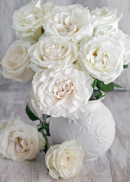 Beautiful fresh roses in a vase on a table . light background
