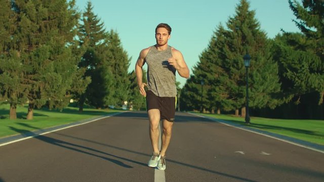 Sport man running in summer park while cardio training outdoor. Fitness workout