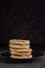 Stack of delicious homemade pancakes on a black plate. Vertical. Copyspace
