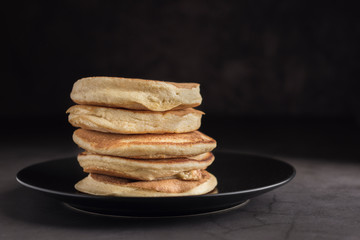 Stack of delicious homemade pancakes on a black plate. Horizontal. Copyspace
