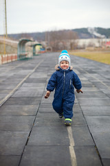 walk in the fresh air. boy child running around the stadium. Winter clothes, happy active childhood.