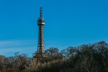 Prague, Czech republic / Europe - February 15 2019: Petrin tower, a famous lookout tower built in 1891 standing on a hill surrounded with trees, sunny winter day, clear blue sky