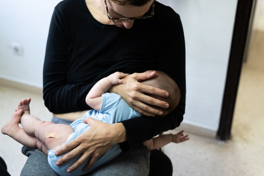 Baby Crying After Vaccination With Band Aid Or Plaster In The Thigh, Comforted By His Mother Who Breastfeeds Him.