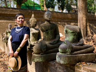 Femme en habit traditionnel Tha&iuml;landais au milieeu des boudhas scupt&eacute;s anciens du Wat Umong