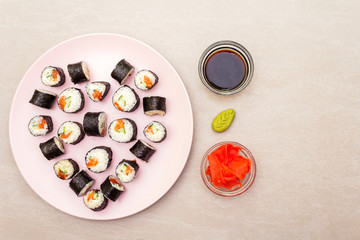Romantic heart sushi dinner. Maki rolls with ginger, wasabi and soy sauce on rosy plate. Concept for Valentine's Day or March 8th. Stone background, top view