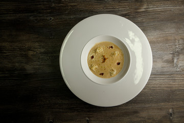 top view beige seafood cream soup decorated with dried squid and soy sauce