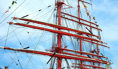 Red masts of a sailing ship against the sky.