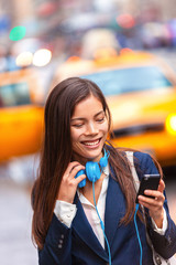 Headphones young woman walking in new york city using phone app listening to podcast or audiobook...