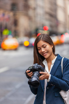 Asian woman photographer taking pictures with professional dslr camera on photography course in New York city street, NYC Usa travel.