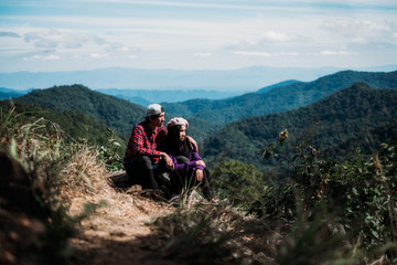 Fototapeta premium Romantic Couple in love sitting on rock watch the sunrise and mountain landscape in morning. Valentine Concept.