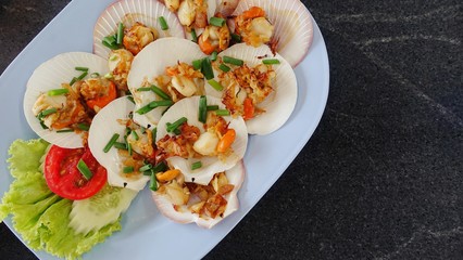 Grilled scallops shell with butter and garlic with cheese and spinach. Healthy food appetizer Baked parmesan scallops. Scallops grilled cheese delicious on the wooden table, Thai sea food.