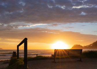 Fototapeta na wymiar Sunrise over beach and park bench