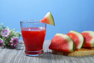 fresh watermelon served in drinking glass and slices on blue colour background