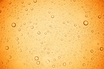 Rain droplets on yellow glass background, Water drops on yellow glass.