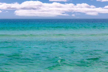 Calm turquoise ocean water under white fluffy clouds