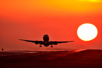 Fototapeta na wymiar 美しい正円の夕日を背景に離陸する航空機　Aircraft to take off with a beautiful full circle sunset
