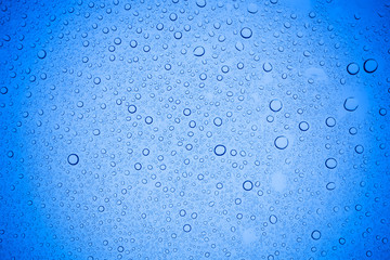 Rain droplets on blue glass background, Water drops on blue glass.