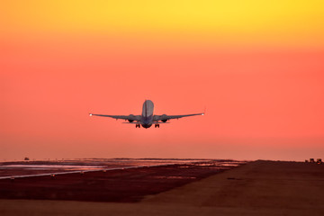 Fototapeta na wymiar 美しいオレンジ色の夕焼けの空へ飛行する航空機　Aircraft flying to the beautiful orange sky sunset sky