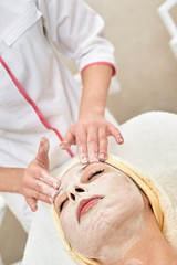 Obraz na płótnie Canvas Young woman with cream on face having facial massage