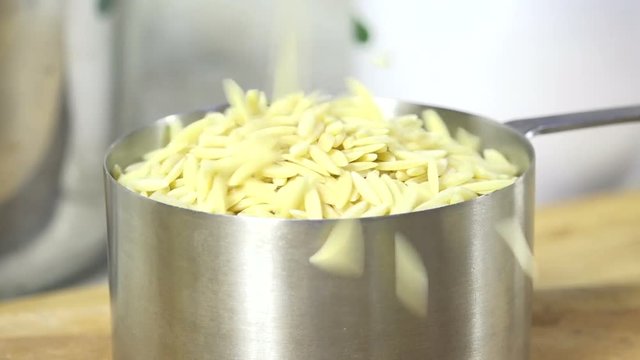 Pouring orzo pasta into a cup, slow motion