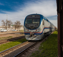modern train moving on rails towards a destination point on a background of blue cloudy sky.