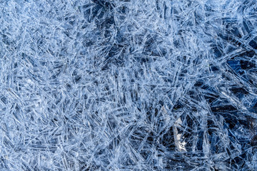 close up of dense ice crystal filled pond surface texture background on cold winter day