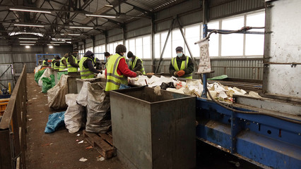 Workers at the waste processing plant. Sorting trash on a conveyor belt.