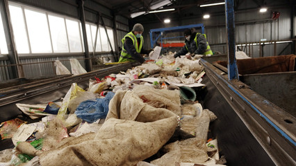 Workers at the waste processing plant. Sorting trash on a conveyor belt.
