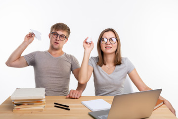 Playful, naughty students with big glasses throwing paper airplanes and crumpled paper sitting at...