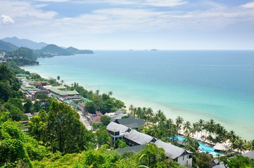 Aerial view of tropical landscape with white sand beach, coconut palm trees, resorts and turquoise tropical sea on Koh Chang Island in Thailand