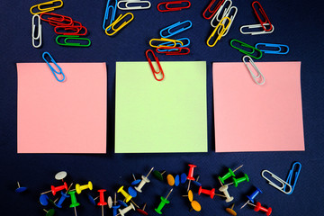 colored paper clips, button and stickers   on a dark blue background. 