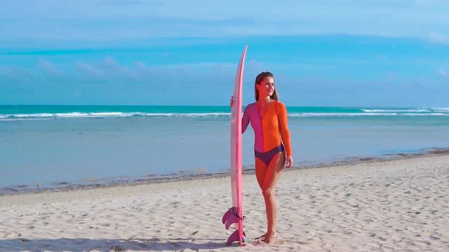 A beuatiful and sexy surfer girl at the beach with her surfboard