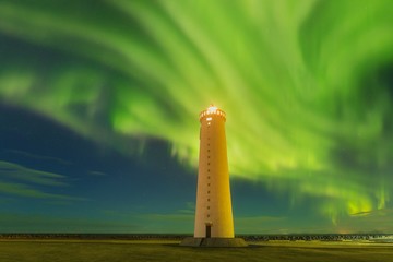 This beautiful northern lights or aurora borealis in Iceland was taken at or around lighthouse near Keflavik during a winter night. Starry sky with polar lights. Green northern lights background