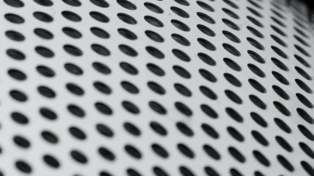 Rotated perforated steel surface background.