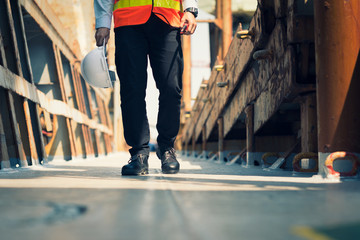 Foreman using walkie-talkie and safety boots to work in Cargo ship