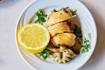 Grilled squid calamari wirh lemon at restaurant on the white plate traditional greek cyprus Mediterranean food dish