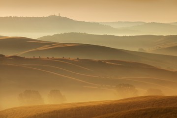 Fototapeta premium Tuscany landscape at sunrise. Typical for the region tuscan farmhouse, hills, vineyard. Italy Fresh Green tuscany landscape in spring time. Beautiful foggy landscape concept