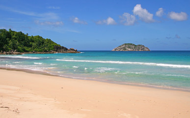 lagoon with clear blue water, tropical greenery and rocks with boulders