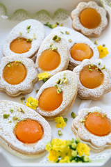 Cookies in the shape of white eggs with apricot yolk with pistachios as homemade decoration