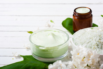 cosmetic creams and white lilac blossom on bright wooden table background