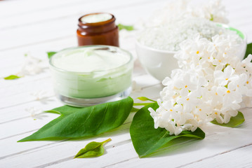 Plakat cosmetic creams and white lilac blossom on bright wooden table background