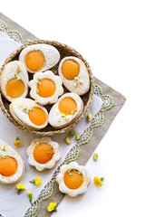 Cookies in the shape of white eggs with apricot yolk with pistachios as homemade decoration