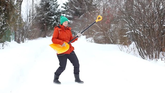 Funny woman playing the snow shovel like a guitar. Her boss sees this and orders her to go back to work - to clean the snow. 