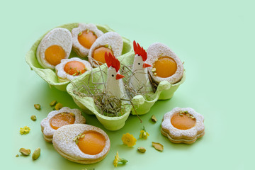 Cookies in the shape of white eggs with apricot yolk with pistachios as homemade decoration