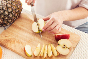 Woman cuts an apple into slices with a knife, close-up