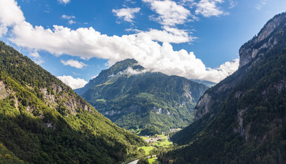 Naklejka premium Helicopter walk over the Swiss Alps in the town of Interlaken. View of the valley, alpine mountains and cloudy sky. Switzerland